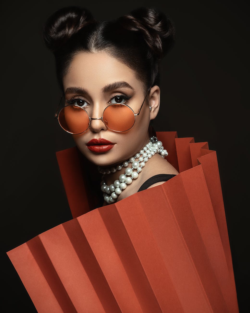 woman wearing sunglasses covering body with orange paper